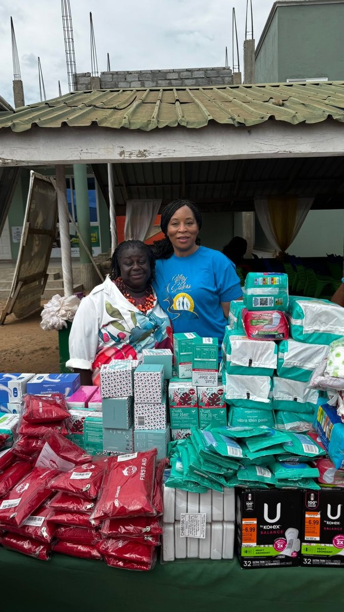 Romona and Afua, MySGA's sister in Ghana, stand together behind a table of sanitary products, first aid kits, and other essential items provided to an orphanage in Ghana.