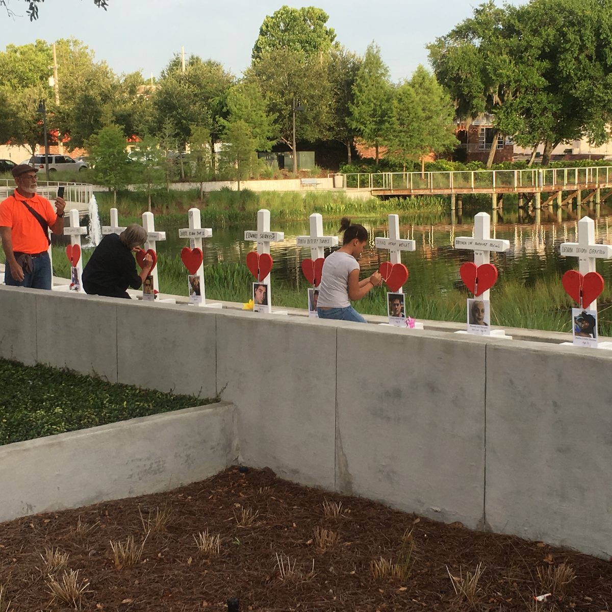 Community members kneel at a row of memorial crosses honoring victims of the Pulse nightclub shooting in Orlando, Florida.